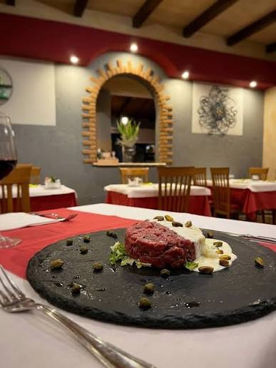 Saletta con tovaglie rosse e piatto di tartare in primo piano