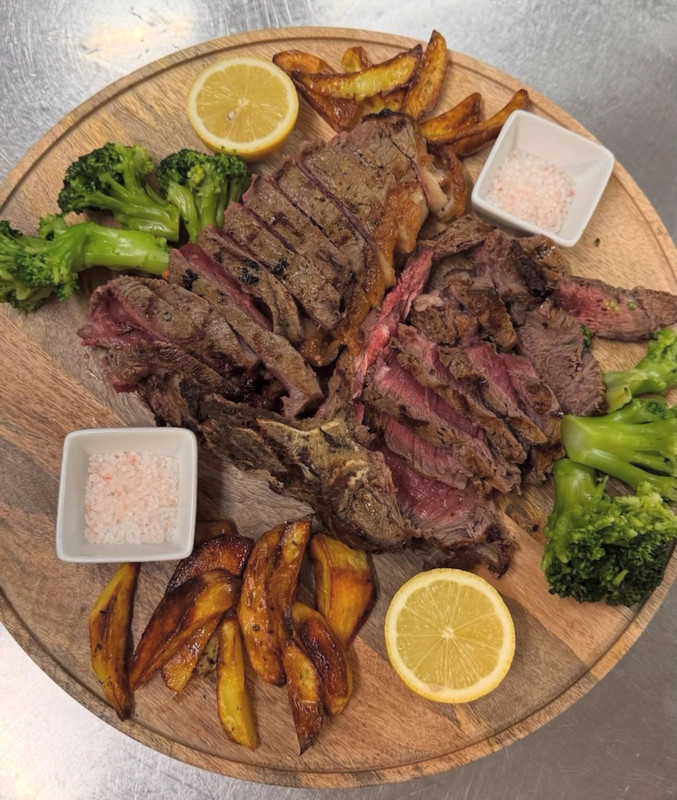 Tagliata di manzo con patate al forno e broccoli servita su tagliere